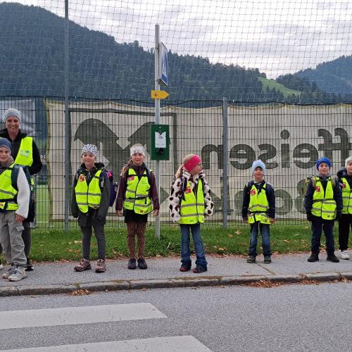 Kinder mit Begleitung warten vor dem Zebrastreifen
