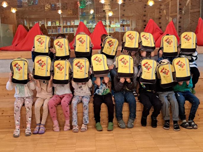Kinder, die sich einen gelben Rucksack vors Gesicht halten