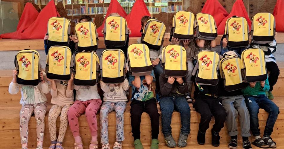 Kinder, die sich einen gelben Rucksack vors Gesicht halten